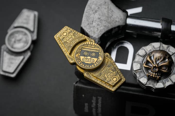 Aztec-themed metallic fidget toy with intricate designs on a dark background, perfect for cultural interest and stress relief.