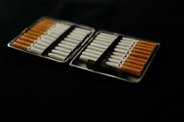 An open cigarette case filled with cigarettes, placed on a dark surface, conveying a mood of smoking and lifestyle.