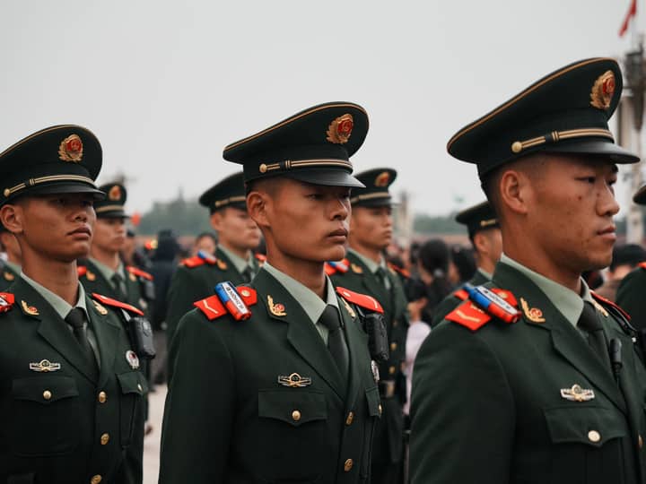 Close-up of military personnel in green uniforms and hats during a parade.