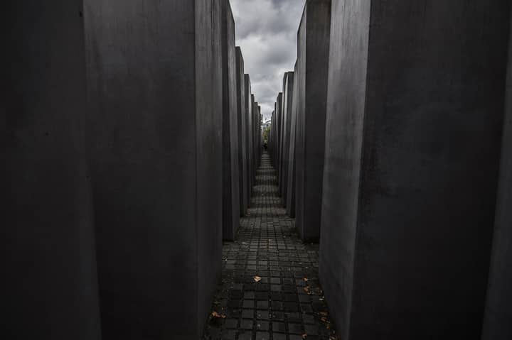 Dramatic view of the Holocaust Memorial in Berlin under a cloudy sky.