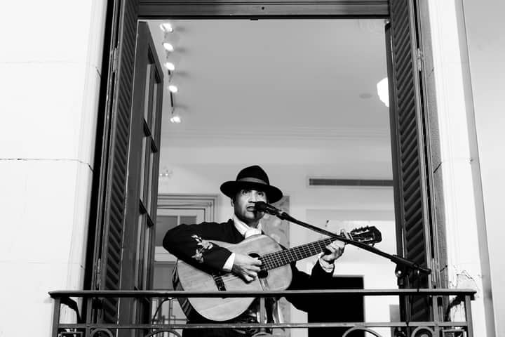 Black and white portrait of a musician playing guitar on a balcony in Buenos Aires.