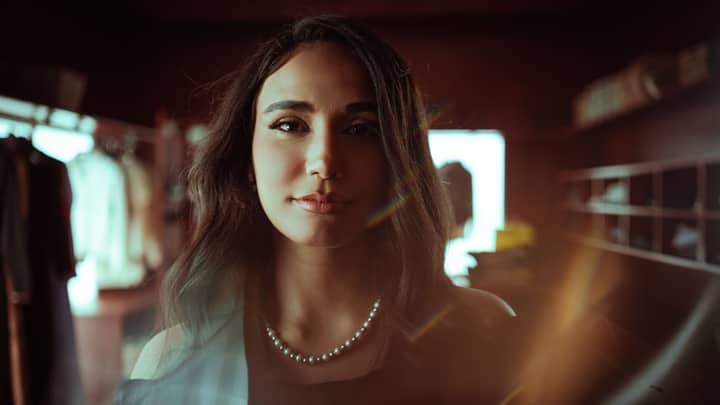 A sophisticated portrait of a woman with a pearl necklace in warm indoor lighting.