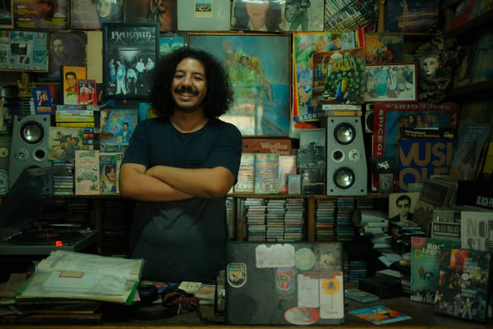 Man standing confidently in a colorful Moroccan vinyl record shop, surrounded by music.