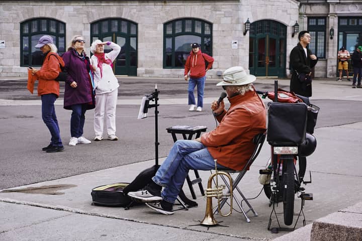 Street performer with a trumpet entertaining tourists in Quebec City.