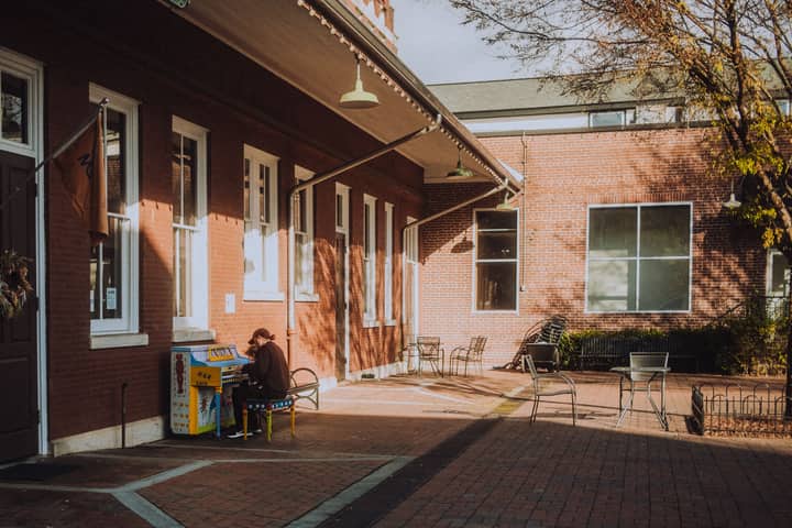 A tranquil courtyard scene with a street piano player, surrounded by charming brick buildings.