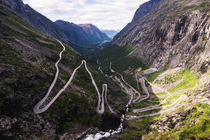 Aerial view of the winding Trollstigen road surrounded by lush mountains in Norway.