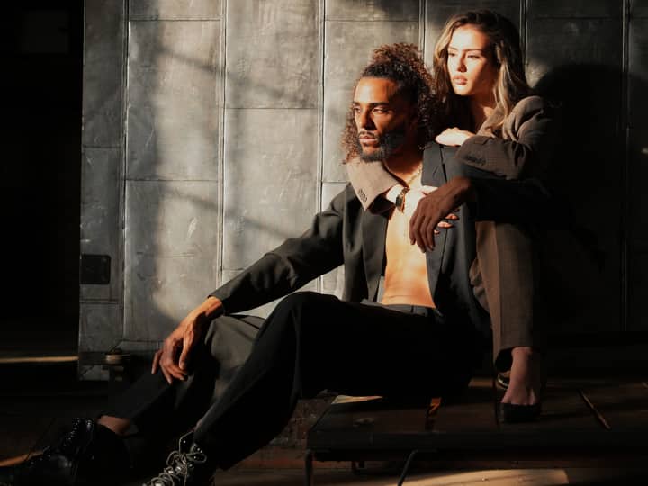 A stylish couple posing in dramatic indoor lighting, exuding elegance and confidence.