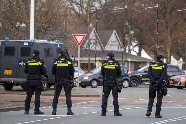 Four police officers stand vigilant on city street near patrol van, ensuring public safety.