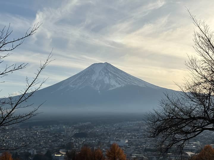 Stunning view of Mount Fuji with a serene cityscape at dusk, surrounded by nature.
