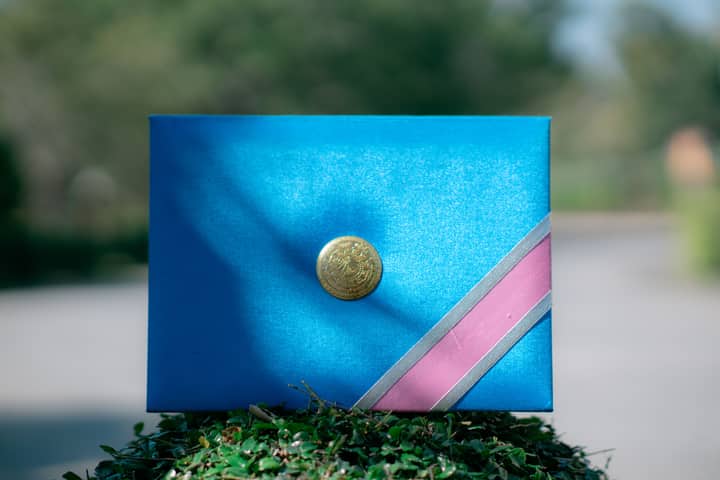 A bright blue and pink graduation certificate on greenery in Lam Sai, Thailand.