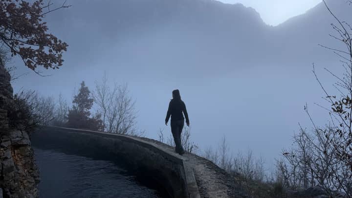 A solitary person walks along a misty mountain path in Dibër County, Albania.