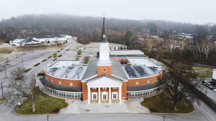 Drone image of a large brick church with steeple surrounded by trees in Tennessee.
