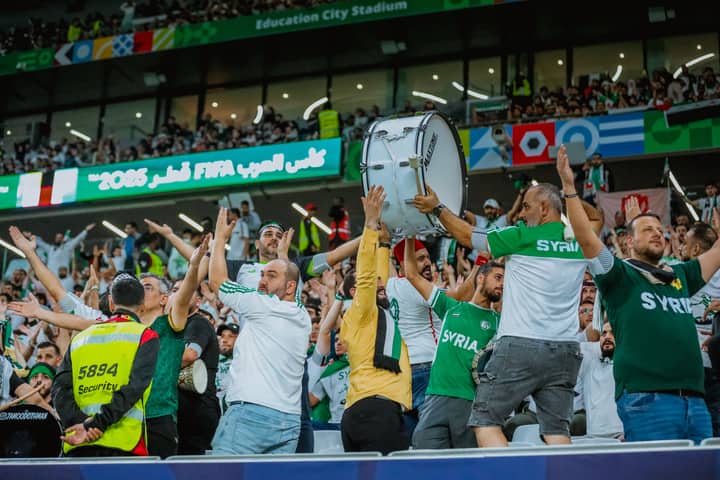 Cheering Syrian fans celebrate at the FIFA event in Doha, Qatar, showcasing lively support.