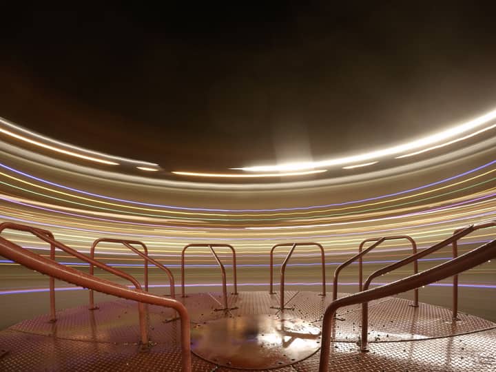 Dramatic long exposure of a carousel at night, creating vibrant light trails.