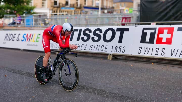 Cyclist in red competing in a race in Harrogate, England, showcasing speed and determination.
