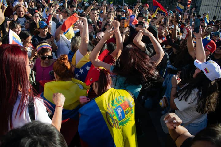 A vibrant crowd of Venezuelan people celebrating with flags under the sun.