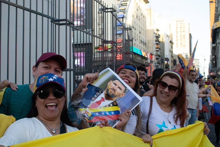 A vibrant street protest in Venezuela, showcasing joyous participants holding a political figure's portrait amid flags and smiles.