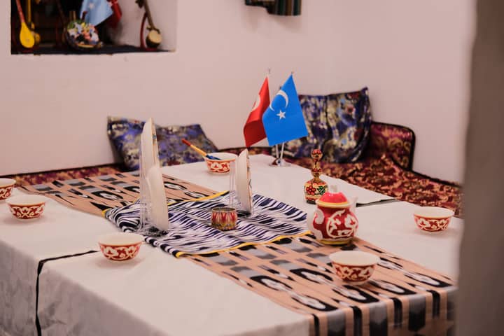 Cozy indoor dining setting with traditional decorations and Turkish, Uyghur flags.