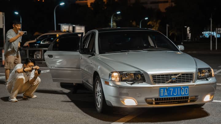 Night scene of photographers capturing a silver car with open door.