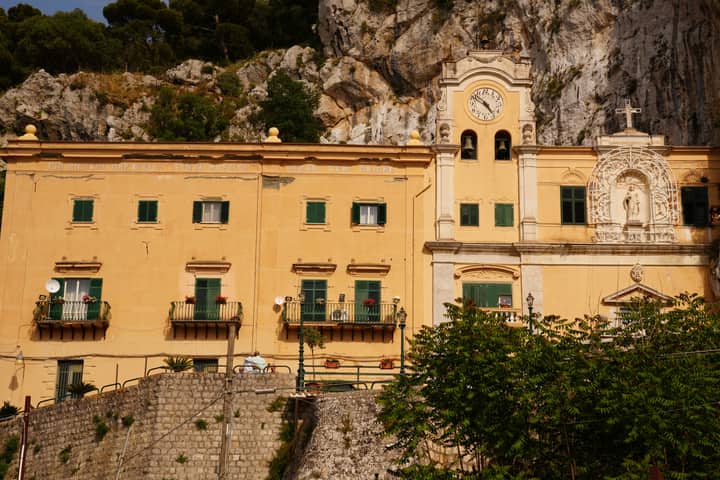 View of the historic Sanctuary of Santa Rosalia set against a rocky backdrop in Sicily, Italy.