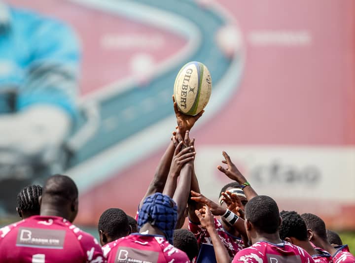 Rugby players reaching for a ball during training, showcasing teamwork and focus.