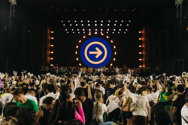 Energetic crowd at a music concert in Pará, Brazil, with stage lights and performers.