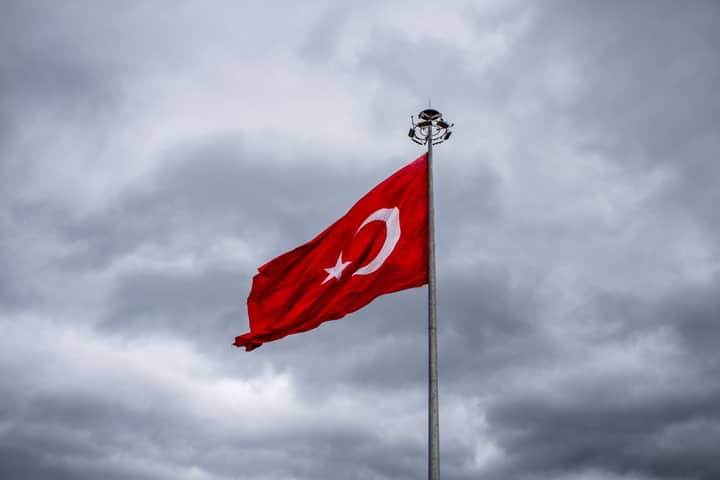 Turkish national flag waving against a backdrop of dramatic gray clouds, symbolizing national pride.