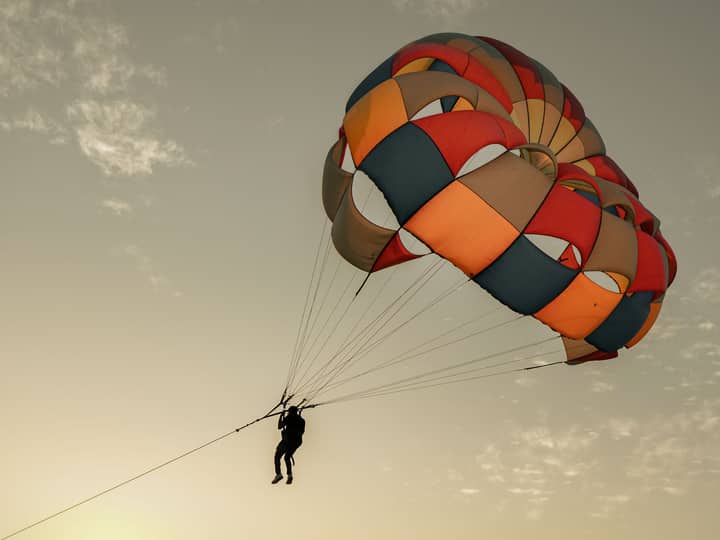 Silhouette of a person parasailing against a dusky sky in Osian, India.