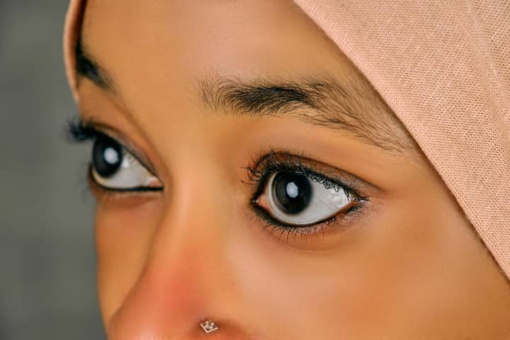 Detailed close-up of a woman's eyes wearing a hijab and nose ring, showcasing beauty.