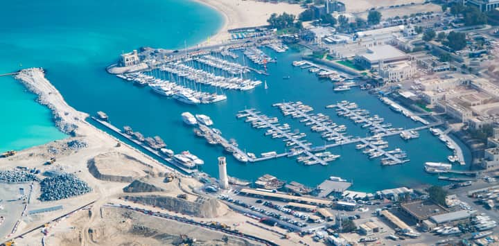 Aerial shot of a vibrant marina with yachts and blue waters in a bustling coastal city.