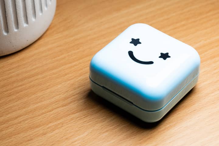 White box with a smiley face and star eyes, placed on a wooden surface.