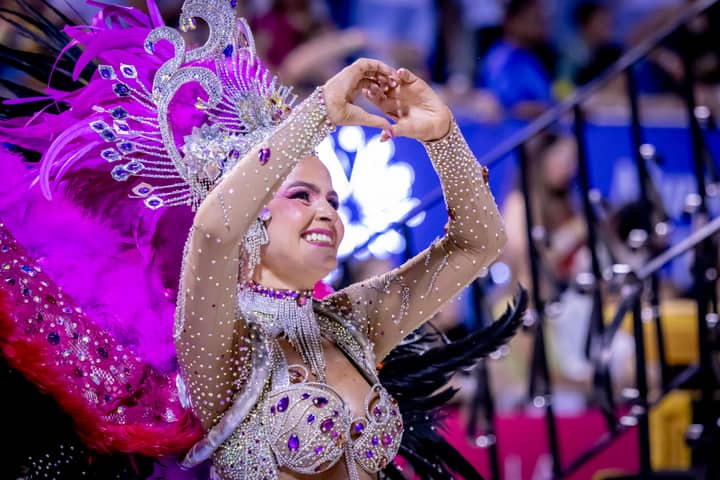 A dancer in colorful costume performs at the Encarnación carnival in Paraguay, showcasing vibrant feathers and intricate designs.