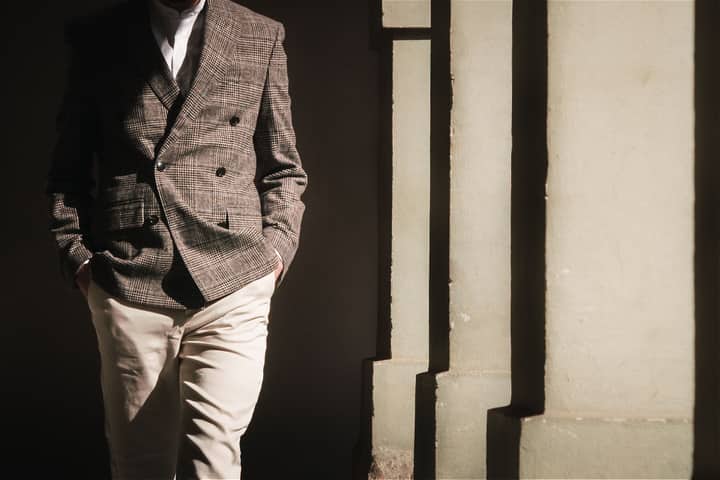 Sophisticated men's fashion with a plaid blazer and khakis, captured in striking sunlight and shadows.