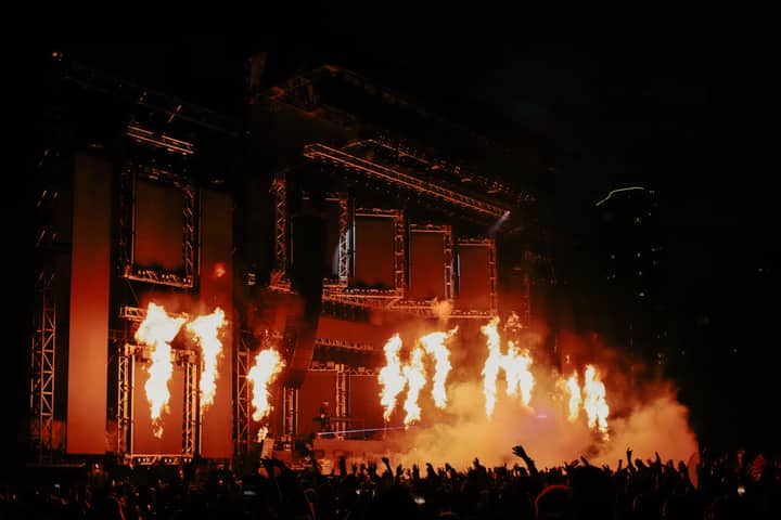 A vibrant music concert in Chicago featuring dramatic pyrotechnic flames and a lively crowd.
