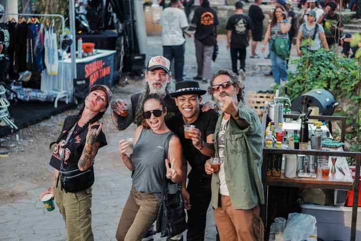 Group of friends enjoying an outdoor event with drinks and laughter, surrounded by vendors.