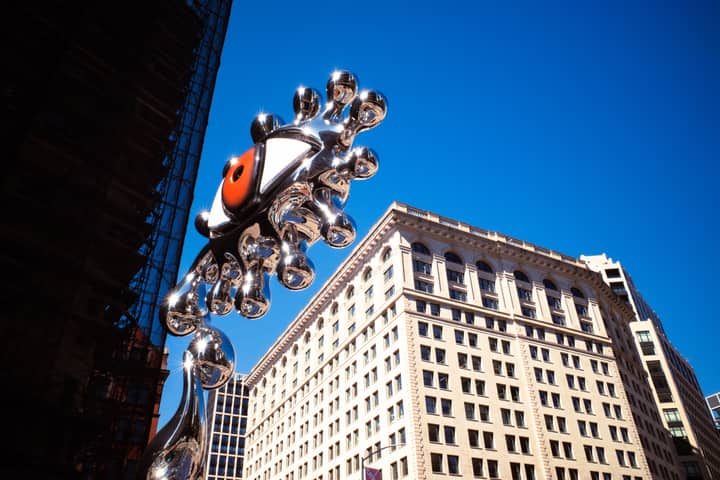 Striking metal sculpture juxtaposed with historic architecture in New York City.