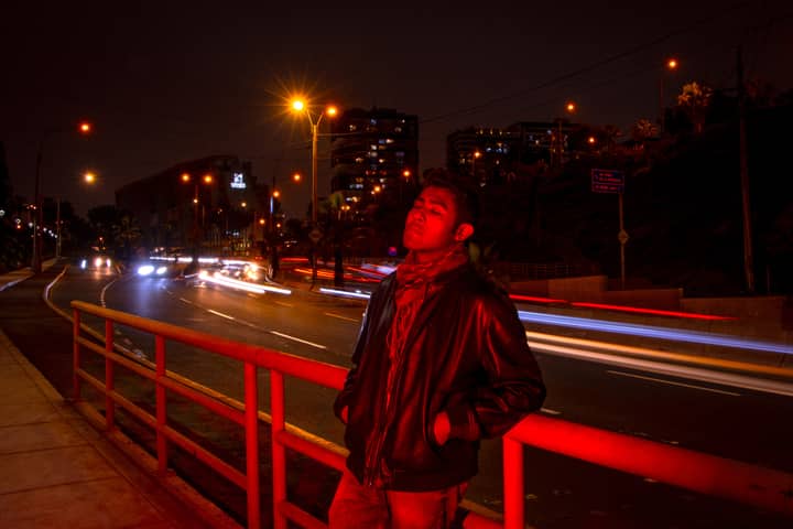 Dynamic night portrait of a man in Lima, Perú with city lights and motion blur in the background.