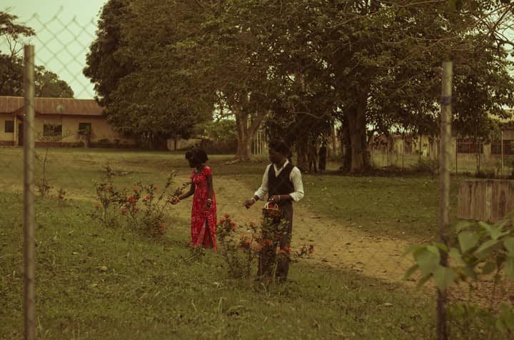 A man and woman picking flowers in a grassy garden in Nigeria.