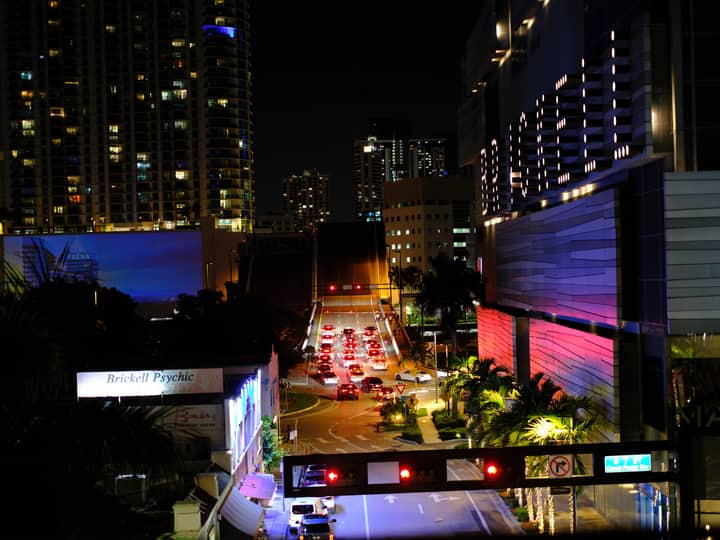 Night view of bustling Brickell with city lights, traffic, and skyscrapers.