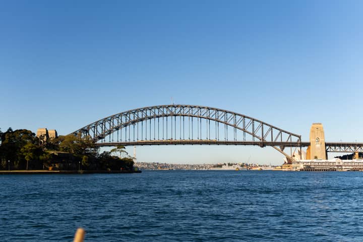 Sydney Harbour Bridge spanning the blue waters under a clear sky during the day.