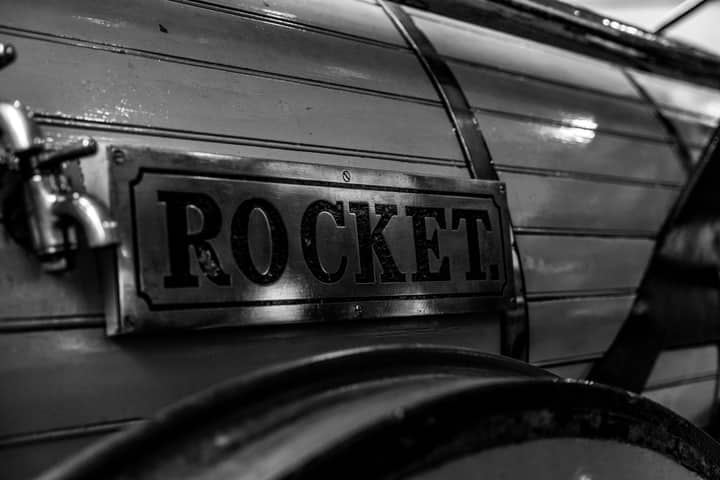Black and white close-up of "Rocket" steam engine sign, showcasing vintage industrial design.