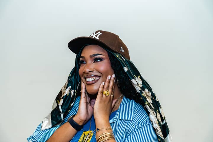 Portrait of a joyful woman wearing a floral headscarf and cap, expressing happiness.