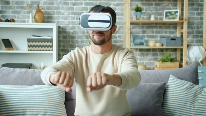 Man using a VR headset in a modern living room, immersed in virtual reality.