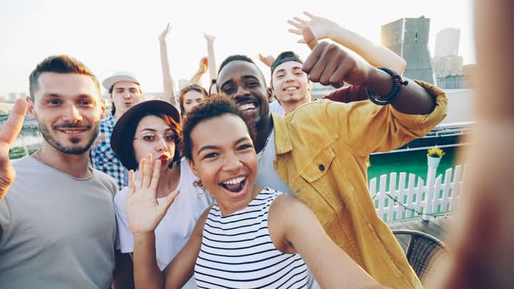 Joyful friends taking a selfie at a rooftop party, celebrating together.