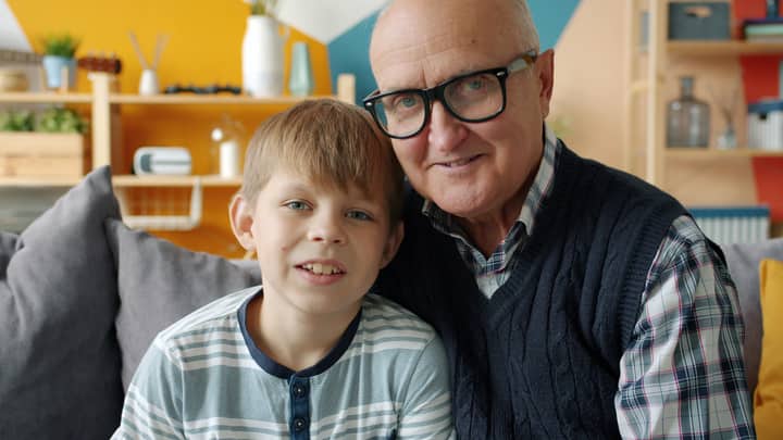 Loving grandfather and grandson smiling warmly in a cozy living room setting.