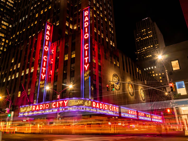 Vibrant night scene of Radio City Music Hall in NYC's Rockefeller Center.