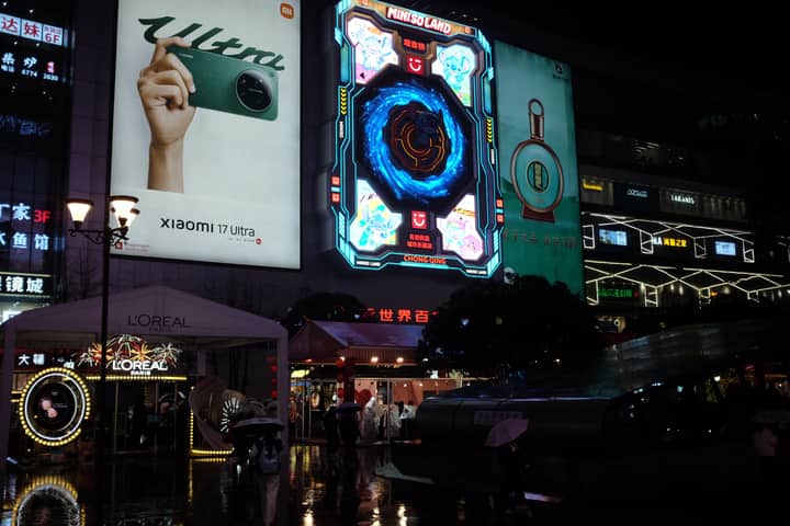 Vibrant urban cityscape at night showcasing illuminated neon billboards and bustling street life.
