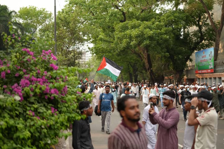 A crowd participates in a pro-Palestine rally in Dhaka, Bangladesh, waving flags in solidarity.