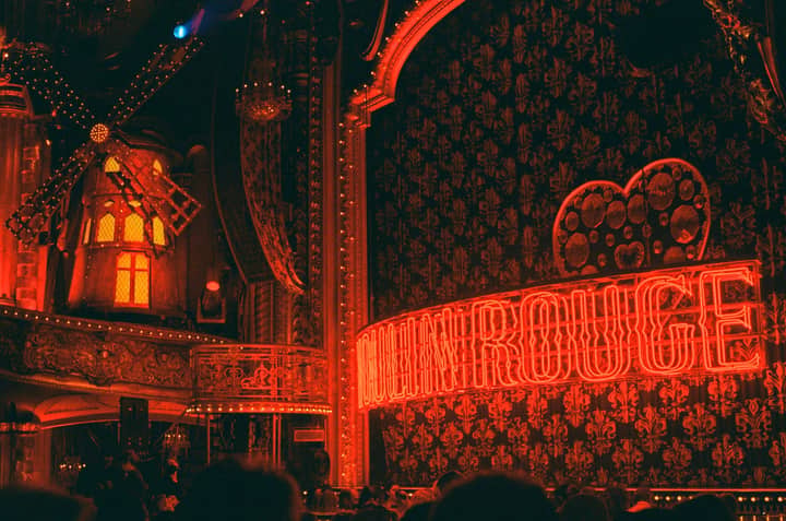 Captivating neon-lit interior of Moulin Rouge theater with iconic windmill in New York City.