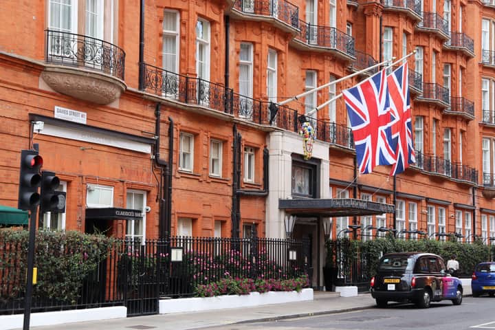 Exterior of classic London hotel on a busy street with Union Jack flags displayed.